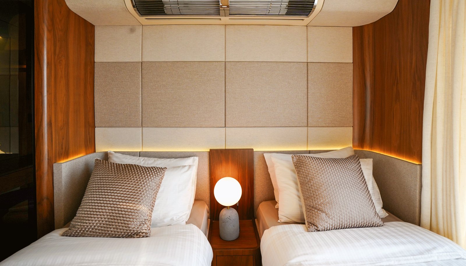 NERO 75 guest room with two single beds under a padded headboard wall